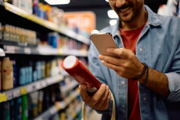 Close up of man scanning product code with cell phone in supermarket.