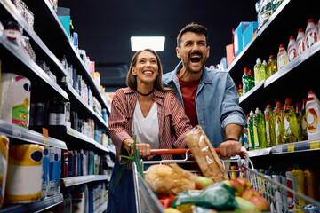 Carefree couple having fun while shopping in supermarket.