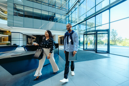 Diverse employees smiling and arriving at modern corporate office