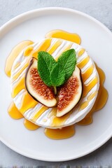 Elevated view of cheese wheel topped with figs mint and syrup on white plate
