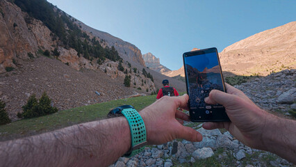 Mountaineer capturing a photo of his companion during the ascent towards the Agujas de Lavasar in the Aragon Pyrenees, surrounded by imposing peaks and rock formations in the mountainous landscape.