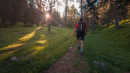 Man ascending to the Agujas de Lavasar from Saravillo, crossing the Lavasar refuge and a landscape of mountains and forests in the picturesque Chistau Valley in the Aragonese Pyrenees.