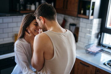 Romantic couple sharing a tender moment in their modern kitchen, enjoying intimacy and connection
