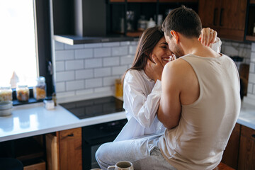 Romantic couple sharing a tender moment in their modern kitchen, enjoying each other's company in a cozy and intimate setting