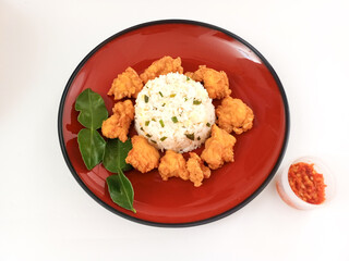 Nasi Ayam Crispy Daun Jeruk or crispy fried chicken with lime leaves rice is served on red plate...
