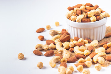 Large assortment of nuts in different bowls on stone table.