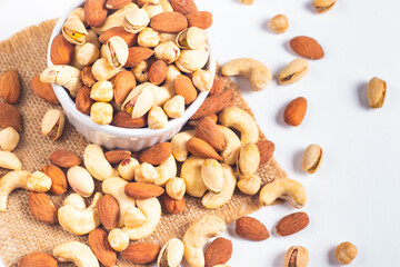 Large assortment of nuts in different bowls on stone table.