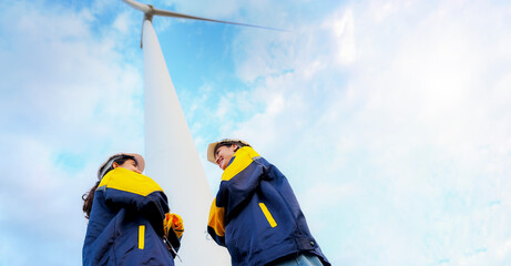 Two beautiful female engineering colleagues and alternative technology engineers surveying wind...