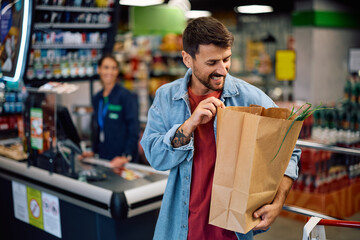 Satisfied supermarket customer carrying paper bag with groceries.
