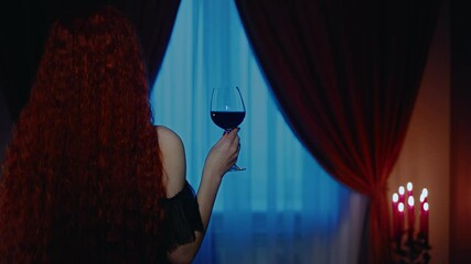 gothic woman long red hair mystical beauty back rear view hand holding glass of red wine close-up. Dark night room. Fantasy lady queen girl vampire sexy lady black dress. candles burning video art  - Powered by Adobe
