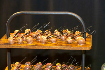 Chocolate-covered cake pops, each skewered with miniature sword picks, are neatly arranged on a...