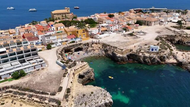 Tabarca Island with colorful buildings, rocky coves, and clear turquoise waters dotted with boats