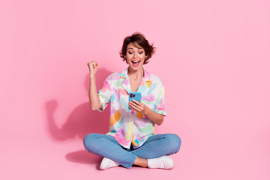 Full size photo of pretty young lady smart phone raise fist wear shirt isolated on pink color background