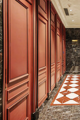Public toilet interior with elegant design in Macau featuring marble floors and red wooden doors