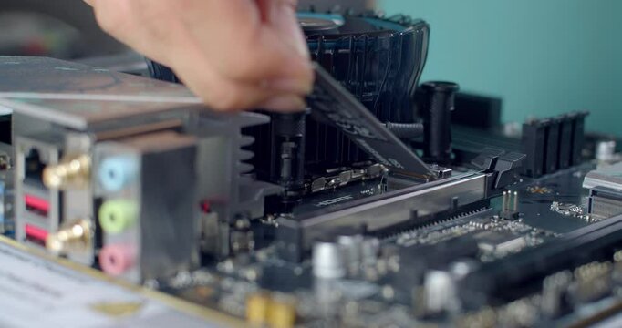 Inserting an M.2 SSD into the motherboard before attaching the heatsink
A high-speed M.2 solid-state drive is slotted into the motherboard&rsquo;s dedicated slot, just before installing its cooling heatsink