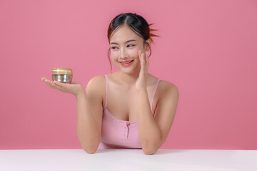 Asian young female presenter beauty advertising model holding jar of face cream to moisturize and...