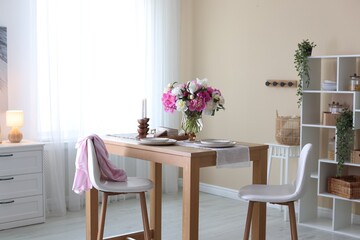 Beautiful table setting with bouquet of peonies in dining room. Interior design
