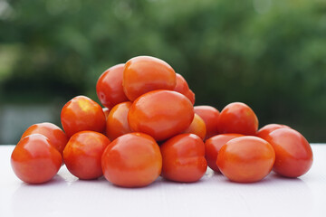 Freshly washed organic tomatoes are stacked on a clean surface outdoors. Concept of pesticide-free garden produce, ideal for healthy cooking and nutritious lifestyle. Natural and rich in antioxidants.
