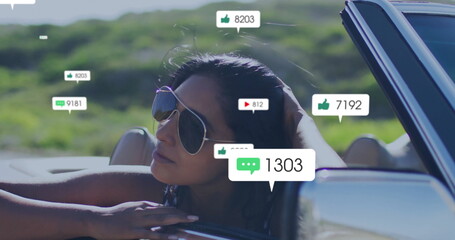 Leaning Indian woman in aviator sunglasses driving convertible through hills, gazing at media icons