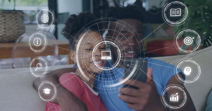 Smiling couple taking selfie in home living room, with smartphone and digital icons
