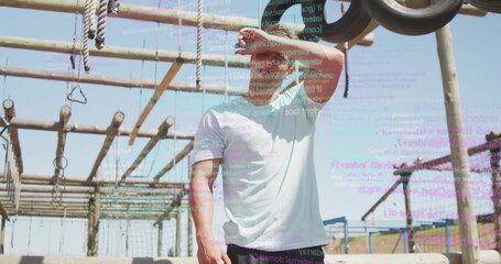 Shielding eyes fit man in athletic wear leaning back on outdoor obstacle course, with code overlay