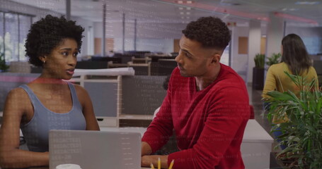 Discussing coworkers wearing casual tops exchanging ideas at open-plan office with silver laptop