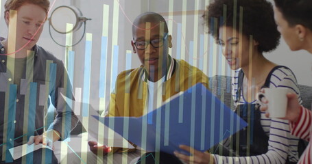 Reviewing group of four colleagues leaning over low table at modern office lounge, with blue folder