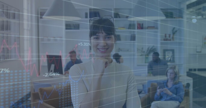 Multiethnic woman analyzing data in open-plan office, with financial charts overlay and monitors - Powered by Adobe