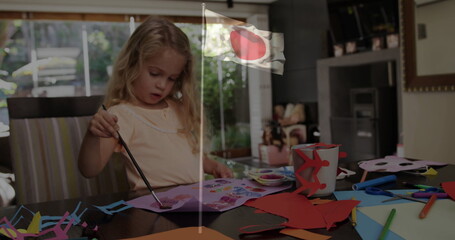 Painting girl holding paintbrush using watercolor palette at home dining table, with craft items