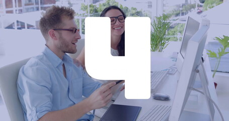Smiling bearded man and woman reviewing tablet at desk, with monitors, potted plants, copy space