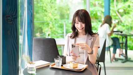 カフェでケーキの写真を撮影する女性
