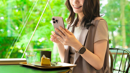 カフェでスマートフォンを使う笑顔の女性