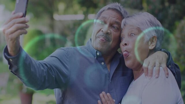 Elderly couple raising smartphone for selfie capturing playful faces while reviewing technology