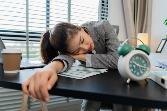 Asian female employee sleepy and tired working from home with a cup of coffee. Sleepy, tired, overworked.