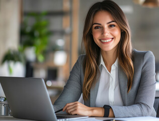 Smiling young businesswoman working on laptop in modern office