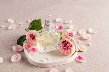 A crystal bottle of women's perfume with the aroma of delicate roses stands on a white tray among...