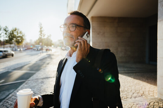 Professional man outdoors talking on phone during morning commute