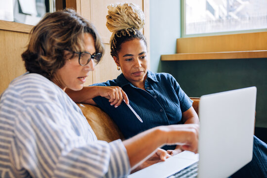 Two women discussing work together while looking at a laptop screen