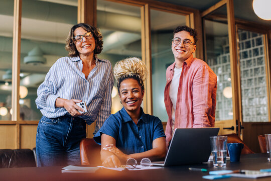 Smiling group of three friends together in a comfortable office space