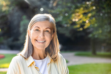 Senior woman smiling brightly in park with natural backdrop