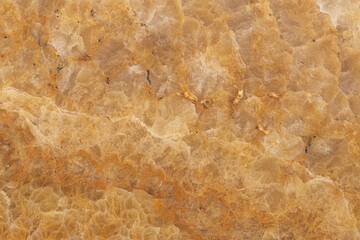 High-resolution close-up of golden brown natural marble surface showing crystalline texture and organic mineral patterns, perfect for backgrounds, tiles, and architectural design.