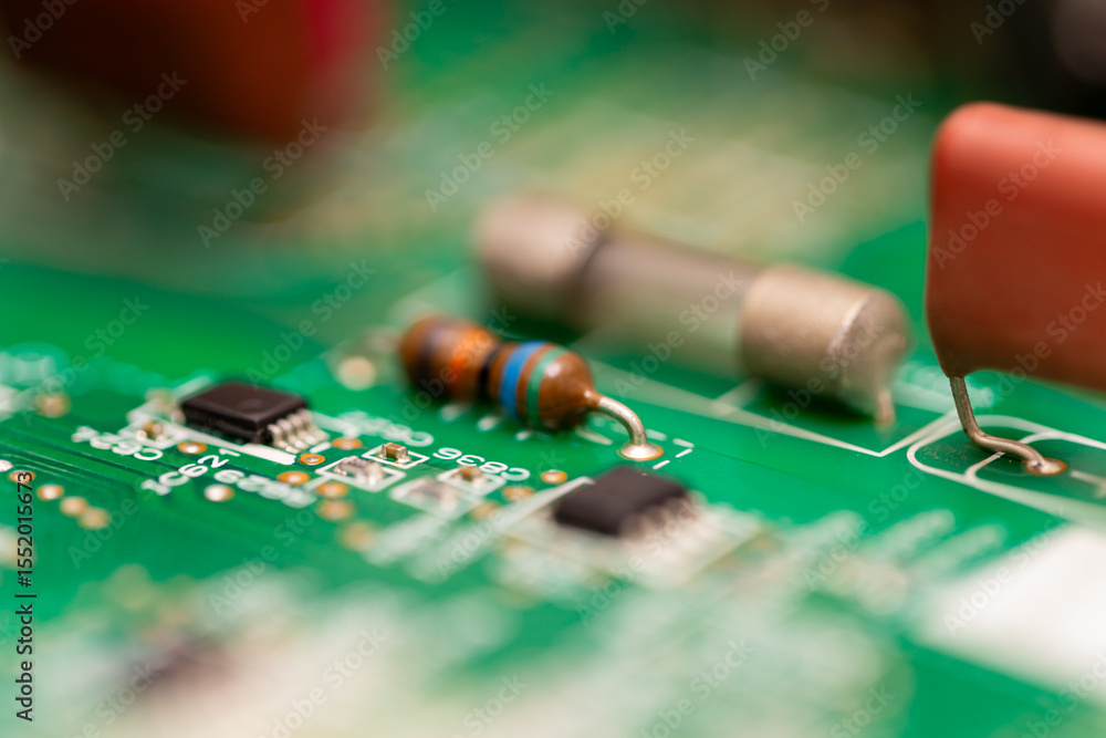 Poster close-up image of a resistor with colored bands and a cylindrical fuse mounted on a green pcb, showi