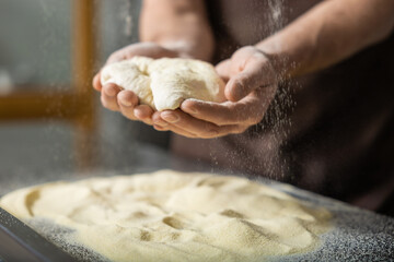 Close up picture of hands with dough for pizza