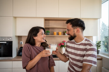 Happy couple drinking milk and having fun in kitchen