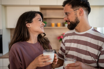 Happy couple drinking milk in modern kitchen, sharing a moment of affection