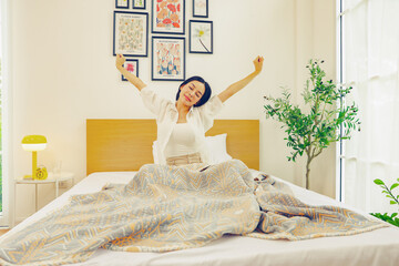 Wake up beautiful young woman early and sat comfortable bed stretching  muscles her arms out just...
