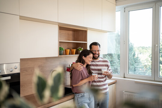 Happy couple enjoying milk in modern kitchen