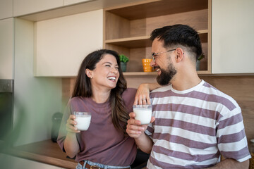 Happy couple laughing and drinking milk in kitchen