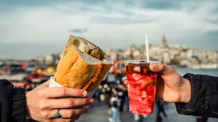 Turkish fish sandwich and pickled drink held with Istanbul city view background