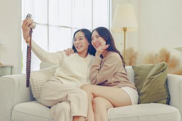 Two female buddies, close friends, use a vintage camera to take pictures themselves having fun on...